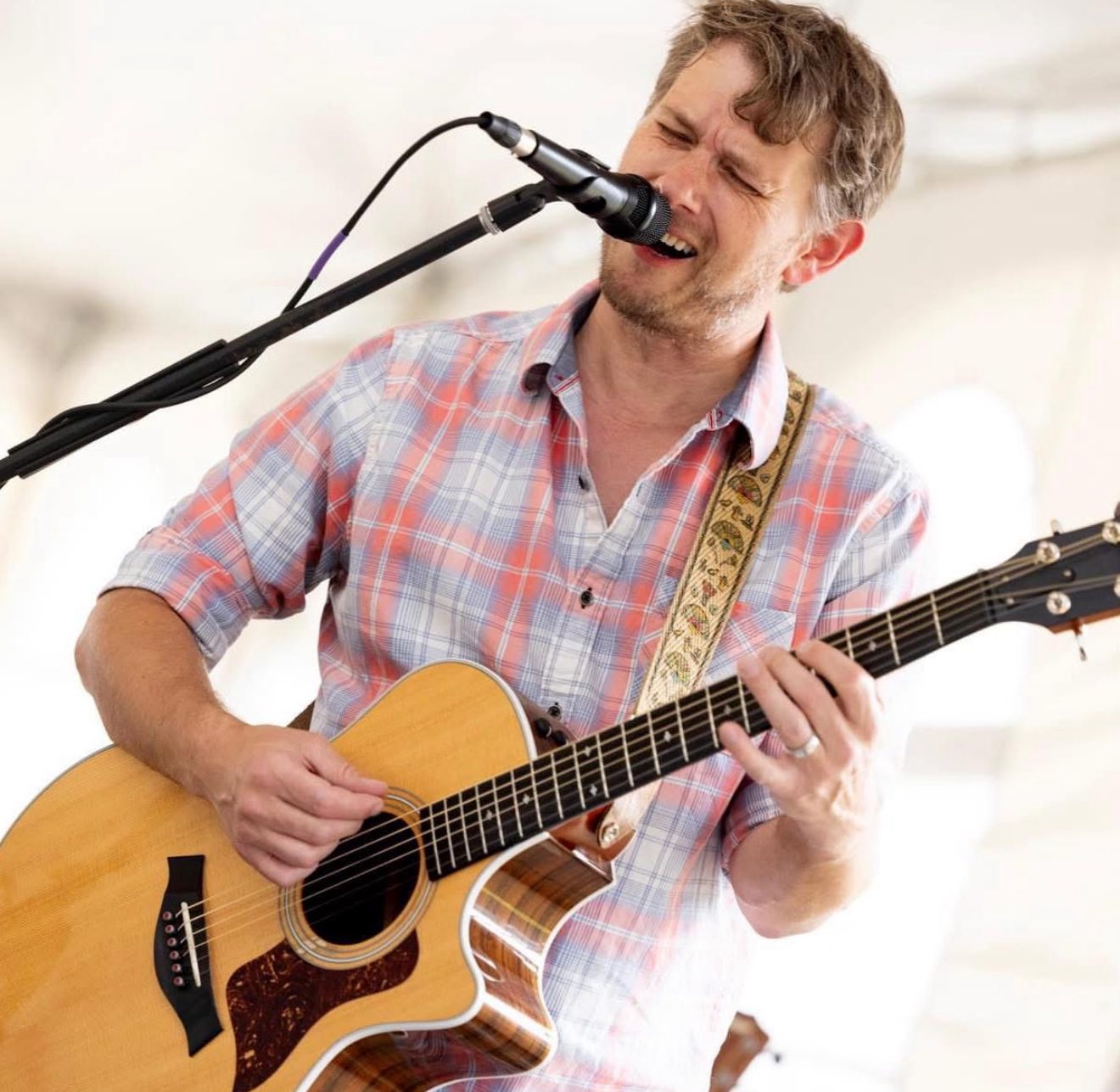 a man singing into a microphone and playing guitar